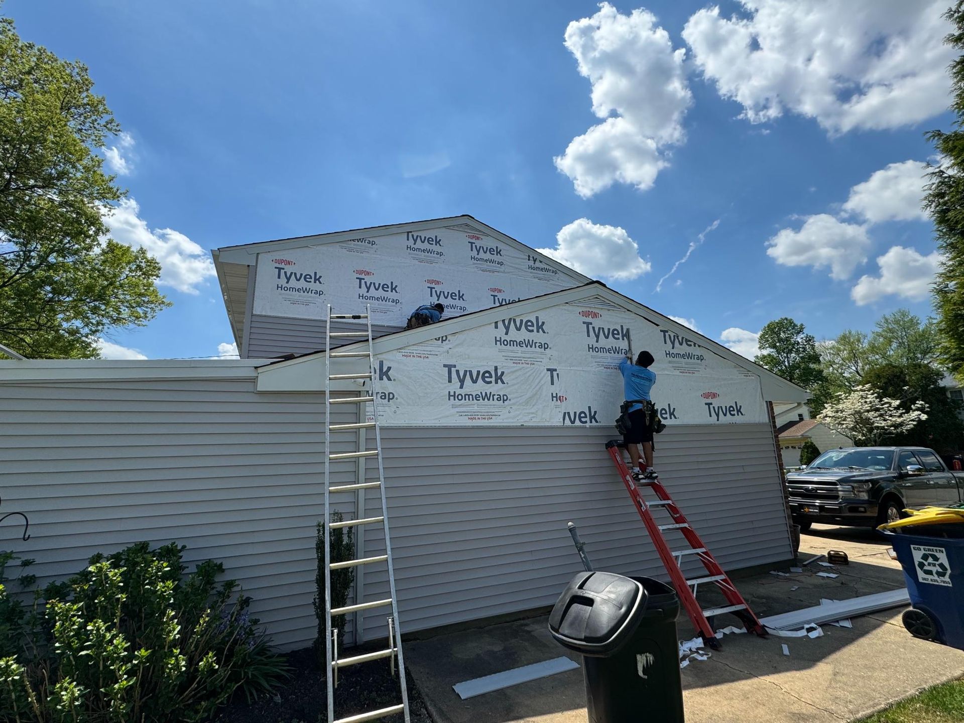 A man is standing on a ladder on the side of a house.