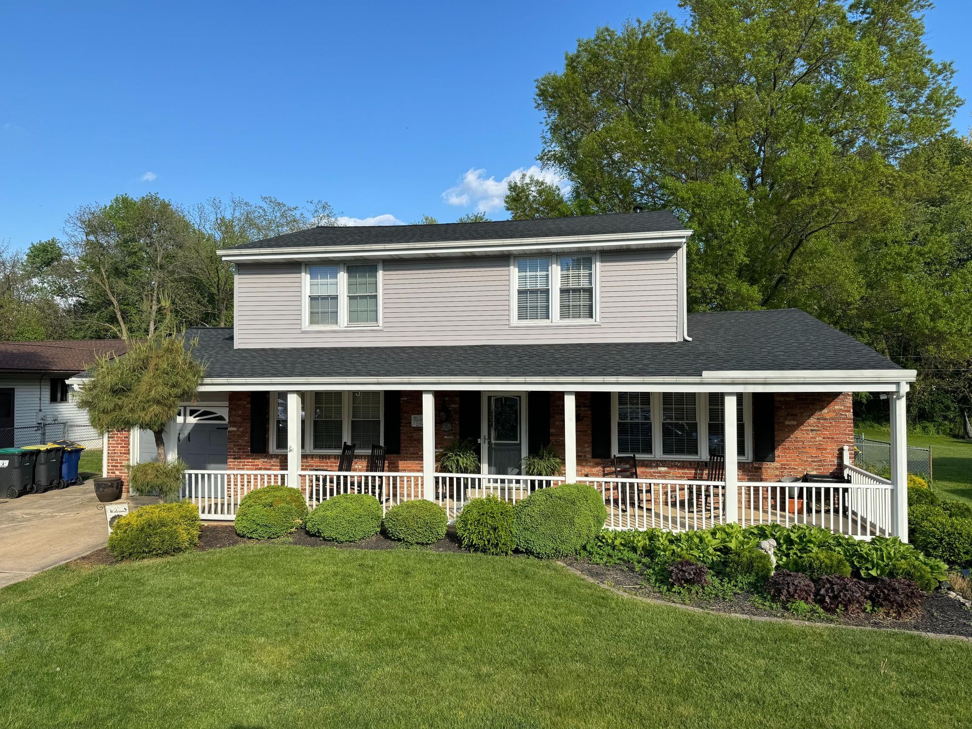 A large house with a large porch and a lush green yard.