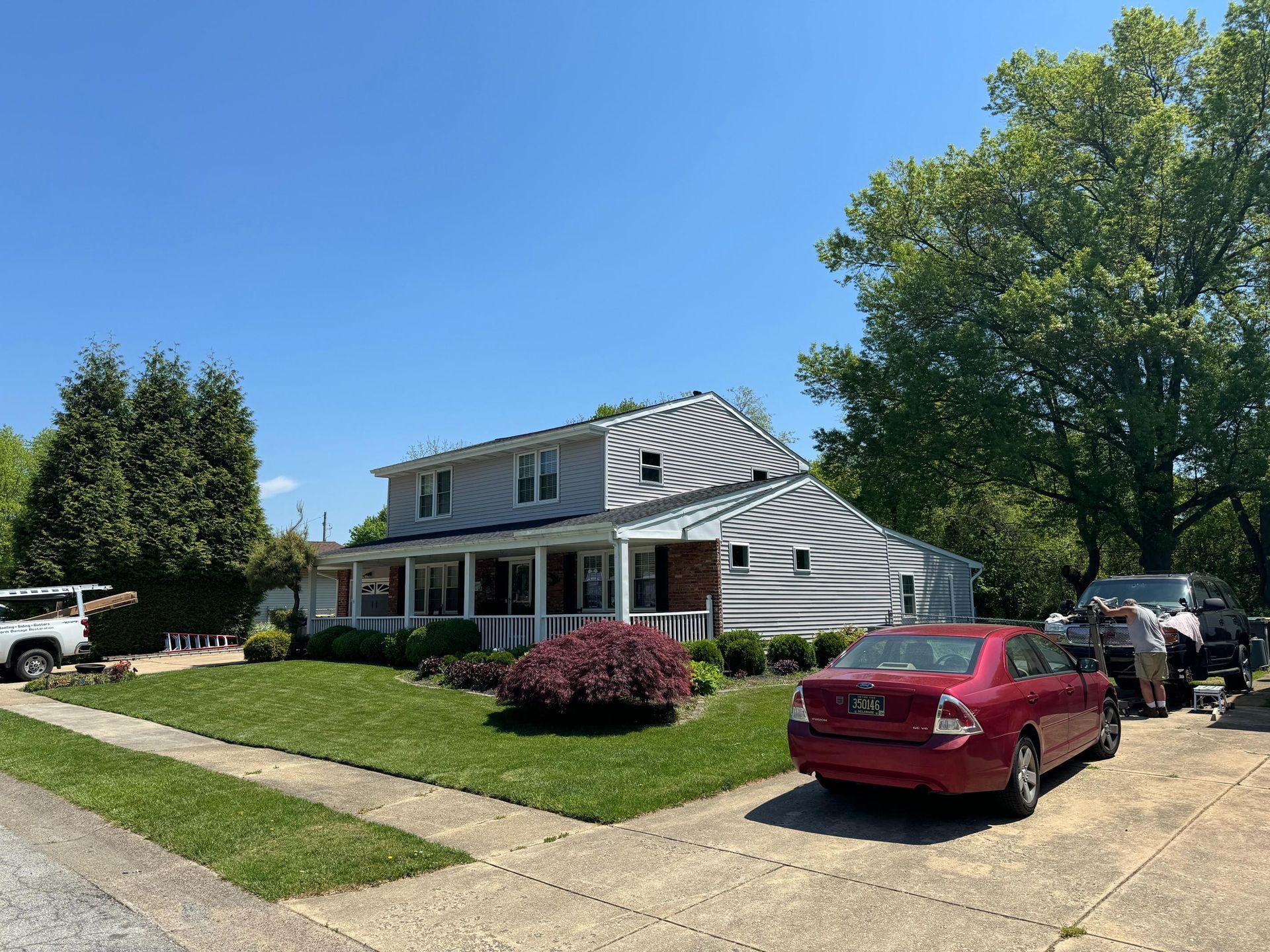 A red car is parked in front of a house on a sunny day.