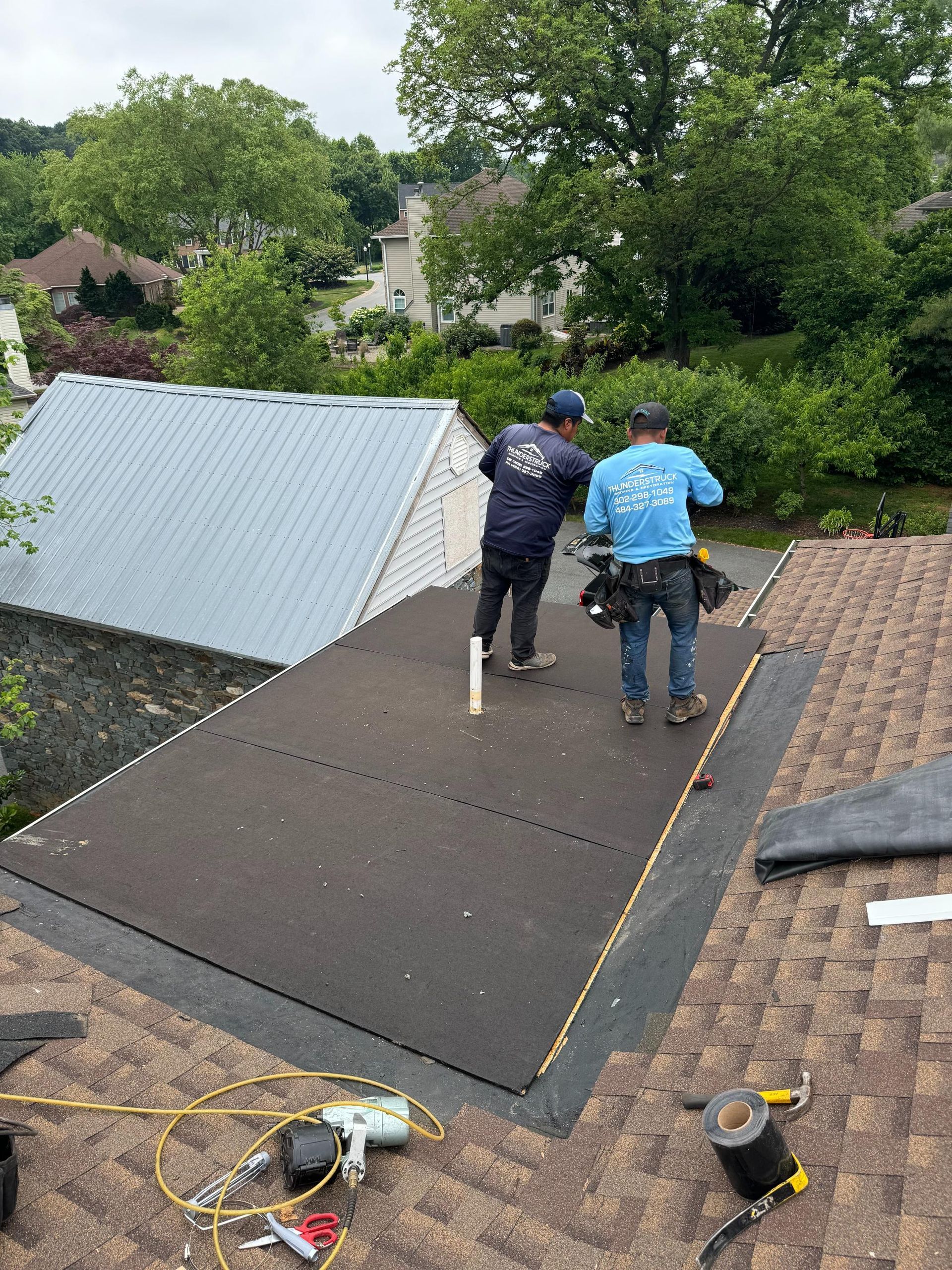 Two men are standing on top of a roof.