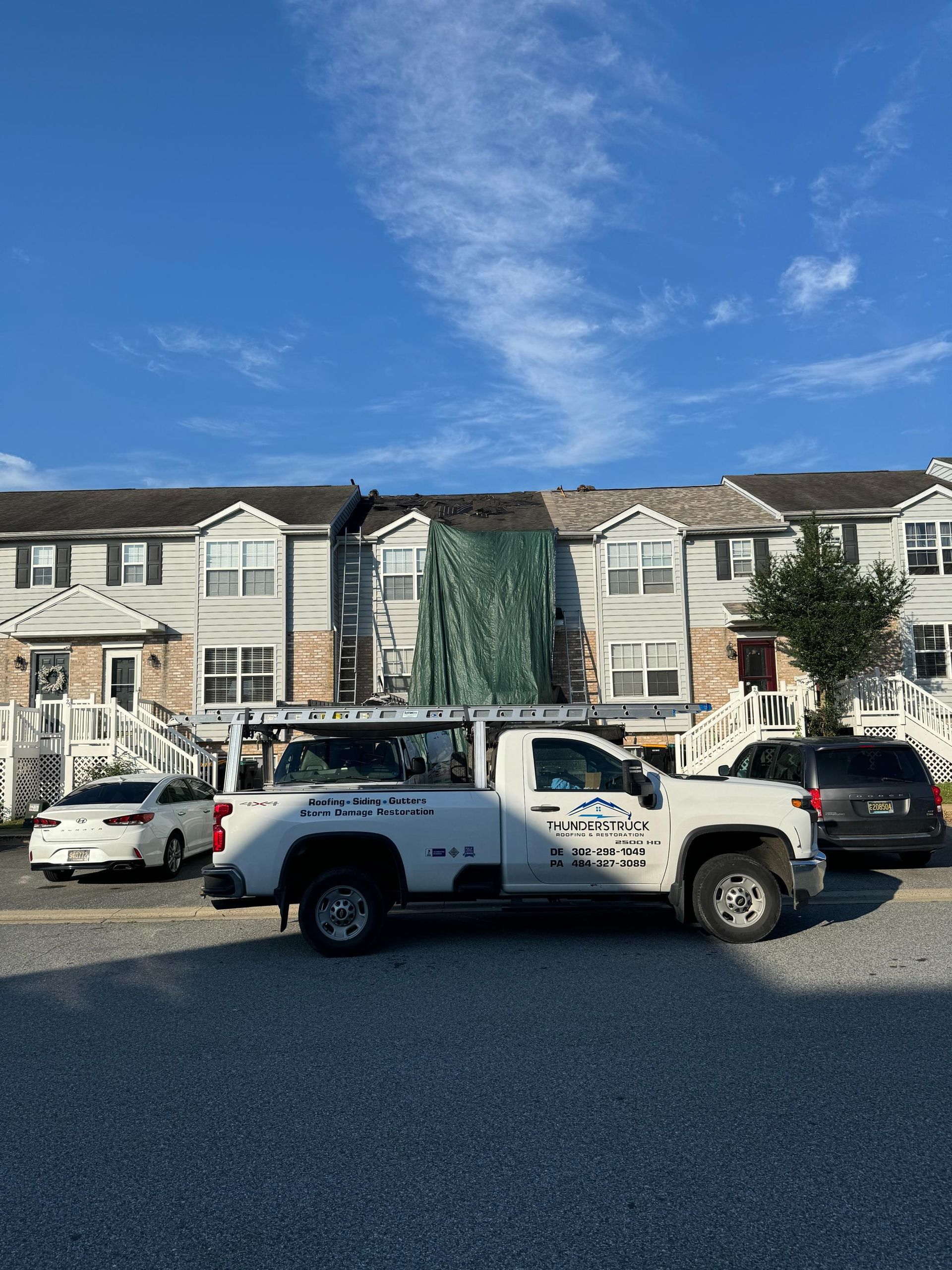 A white truck is parked in front of a row of houses.