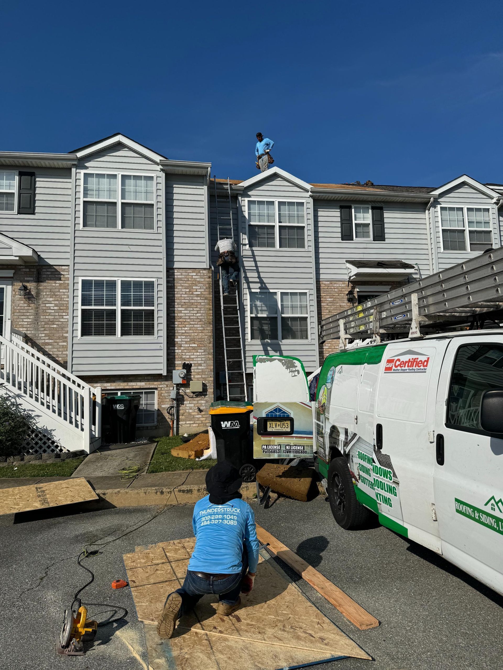 A man is working on the roof of a building next to a van.