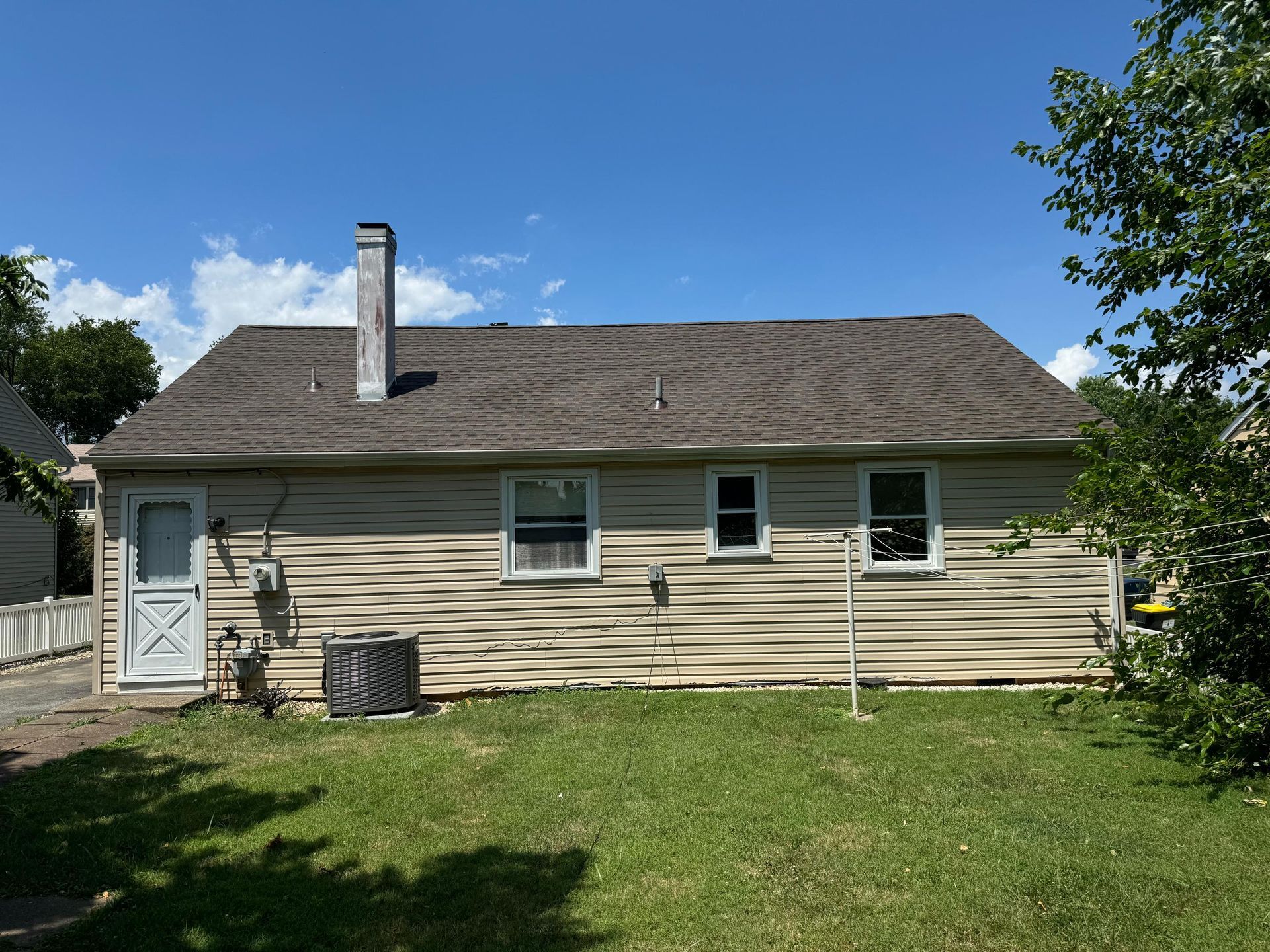 The back of a house with a roof and a chimney.