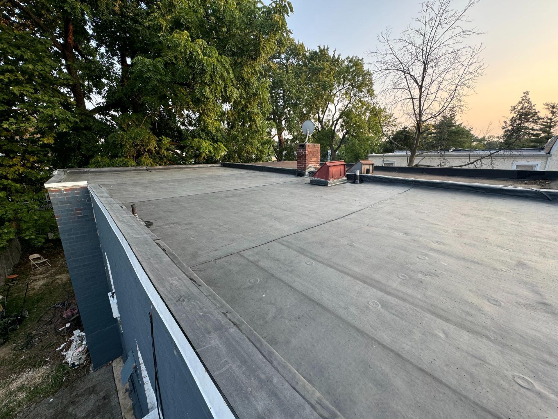 A roof with a chimney on it and trees in the background.