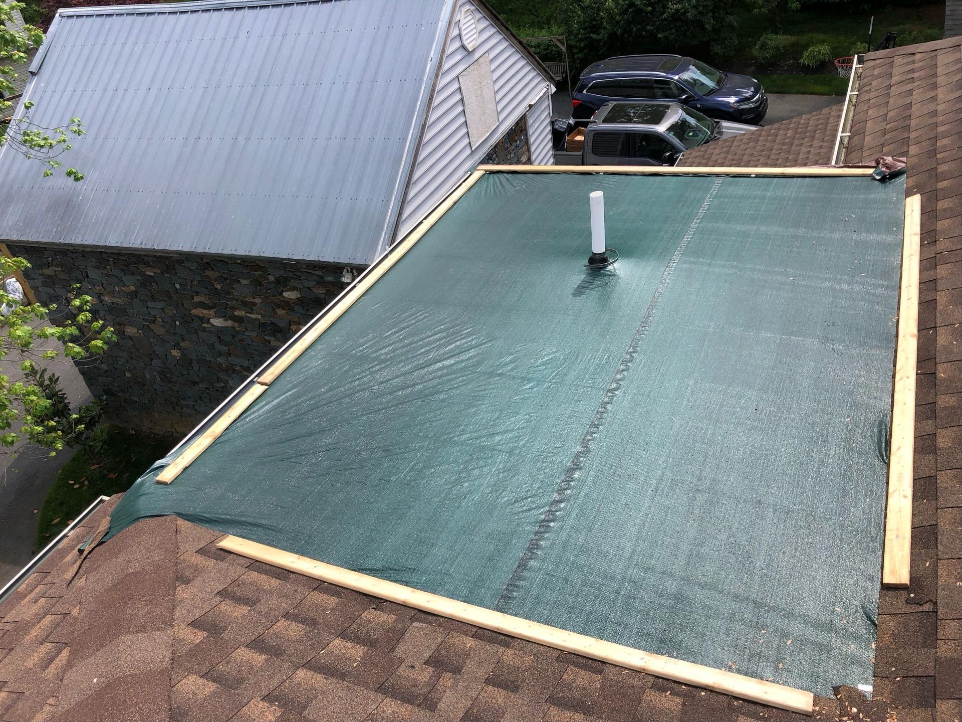 A roof with a green tarp on it is being installed.