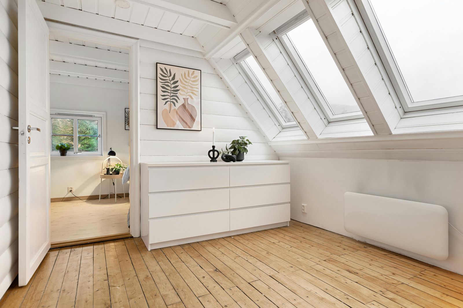A room with a dresser and a picture on the wall.