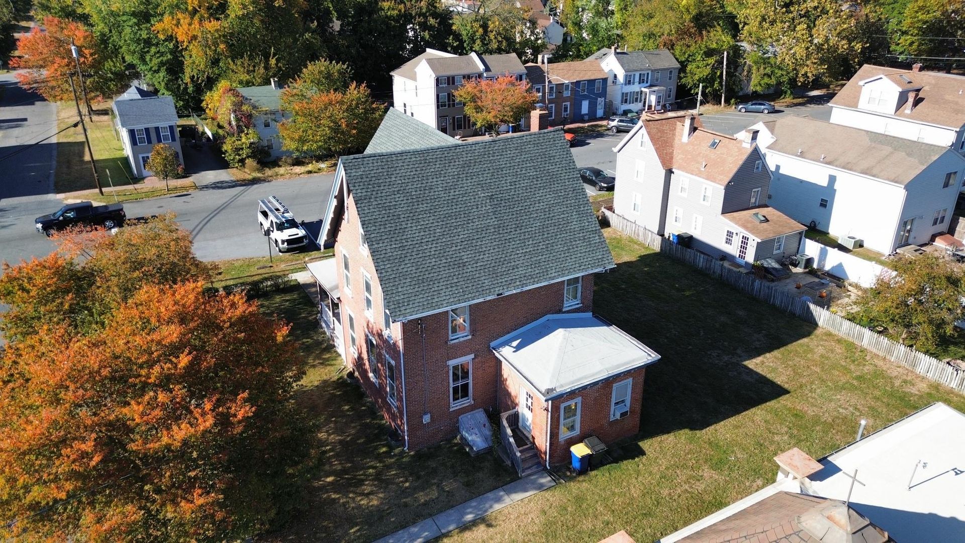 An aerial view of a brick house with a green roof in a residential area.