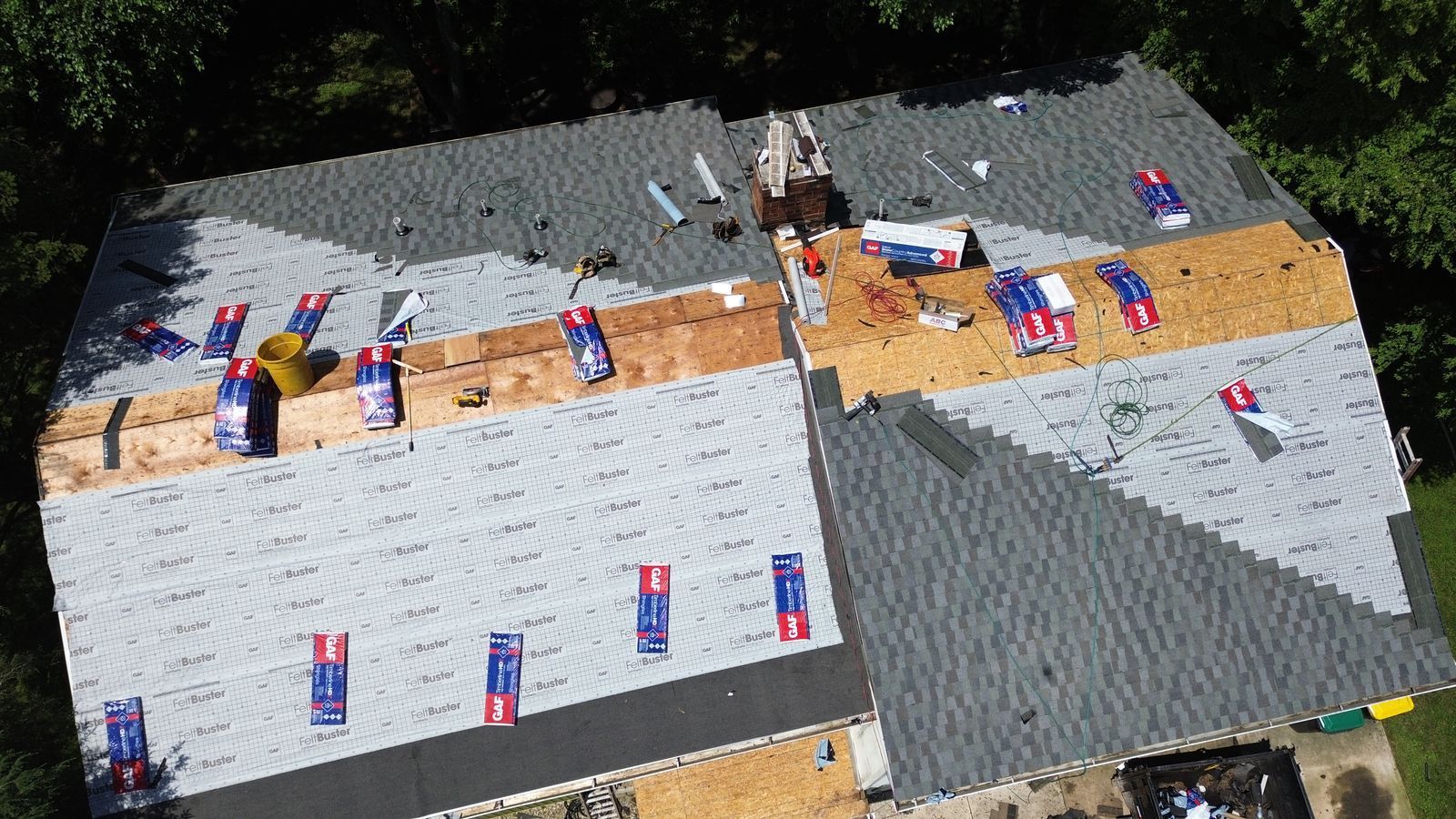 Aerial view of a house roof partially under construction; new shingles and materials visible.