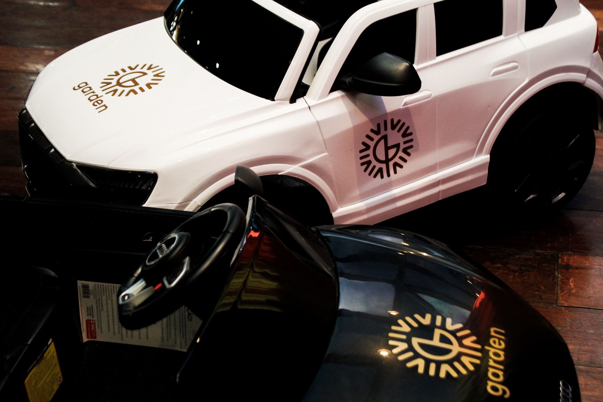 Dois carrinhos de brinquedo, um branco e um preto, com o logotipo 