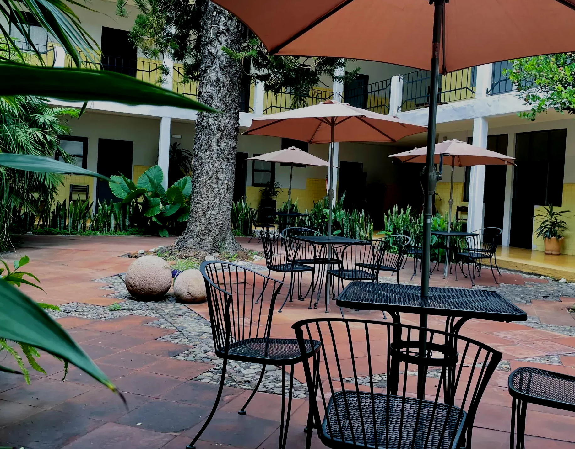 Un patio con mesas y sillas bajo sombrillas.