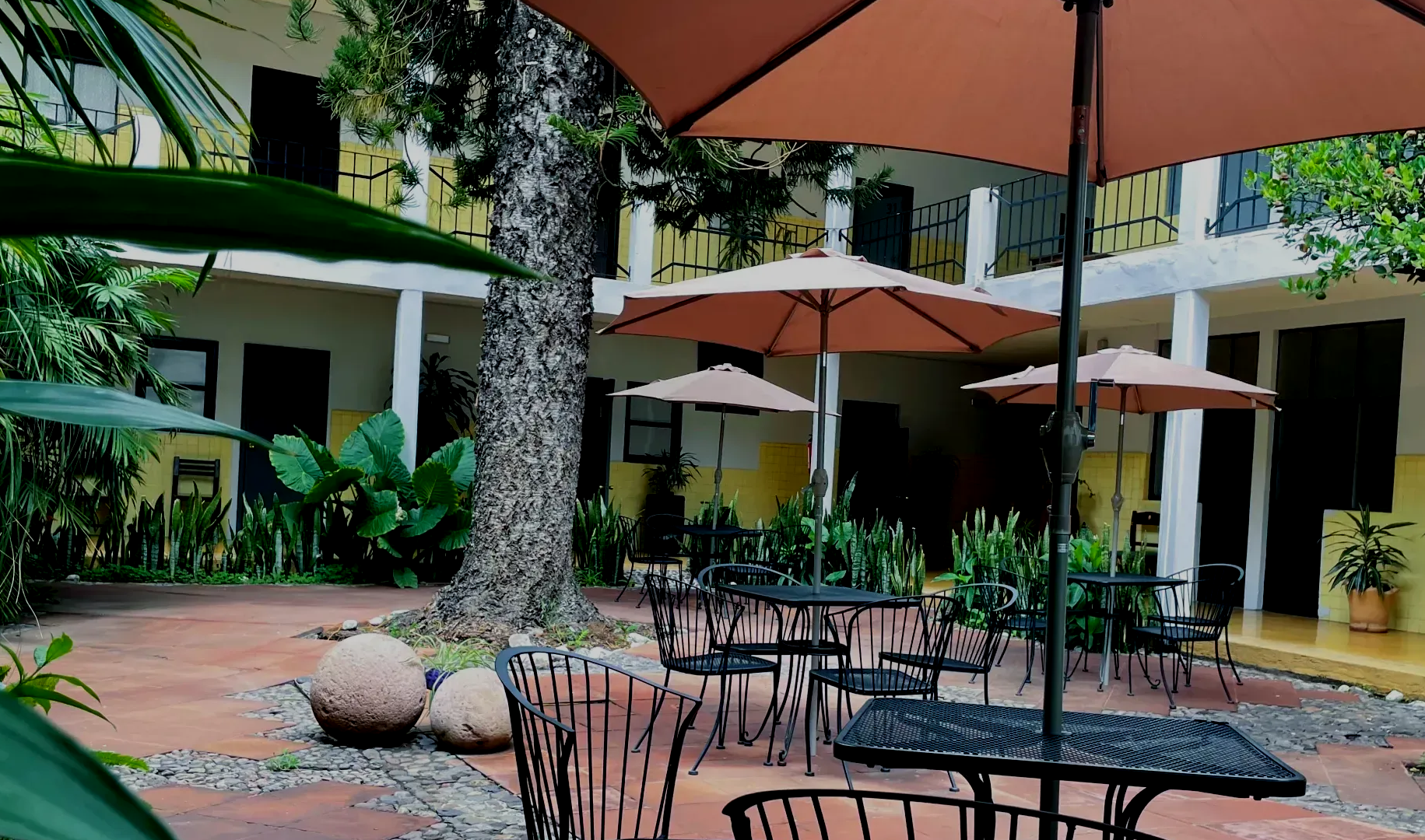 Un patio con mesas y sillas bajo sombrillas.