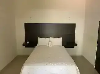 Hay una cama en el medio de la habitación con un cabecero de madera.
