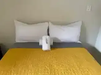 Una cama con una manta amarilla y almohadas blancas