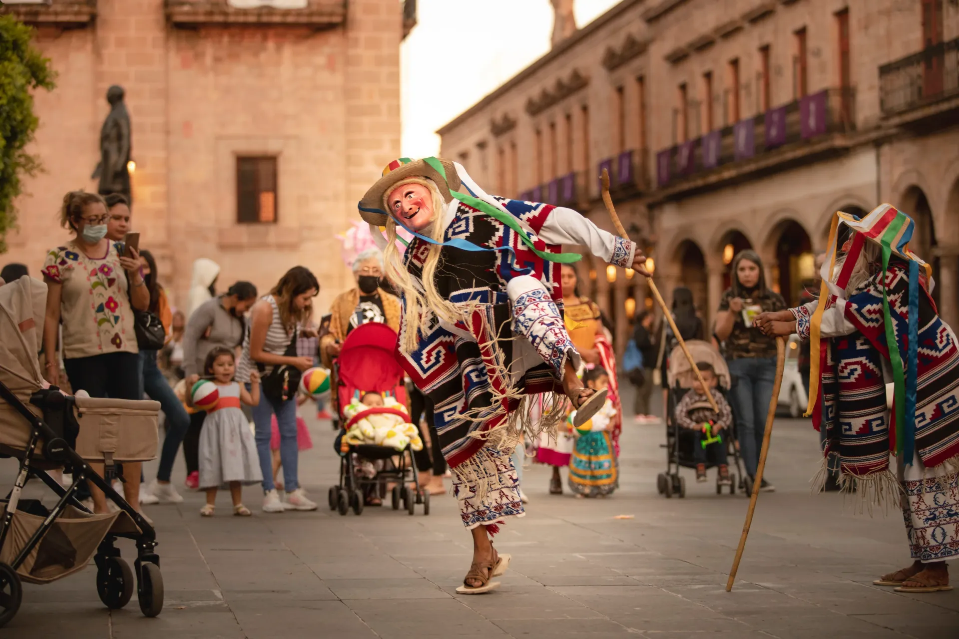 A group of people are dancing on a street in front of a building.