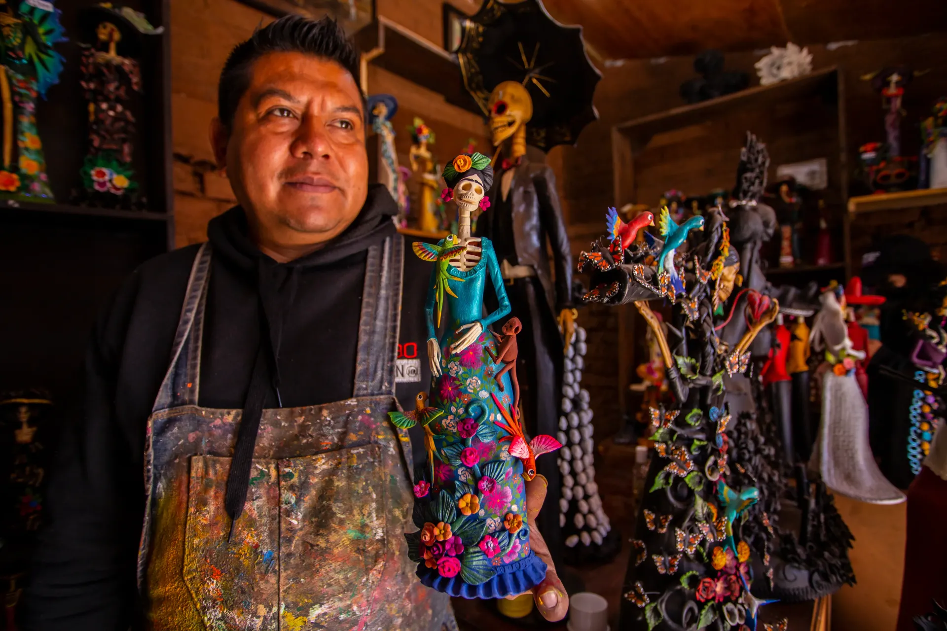 A man in an apron is holding a doll in a store.