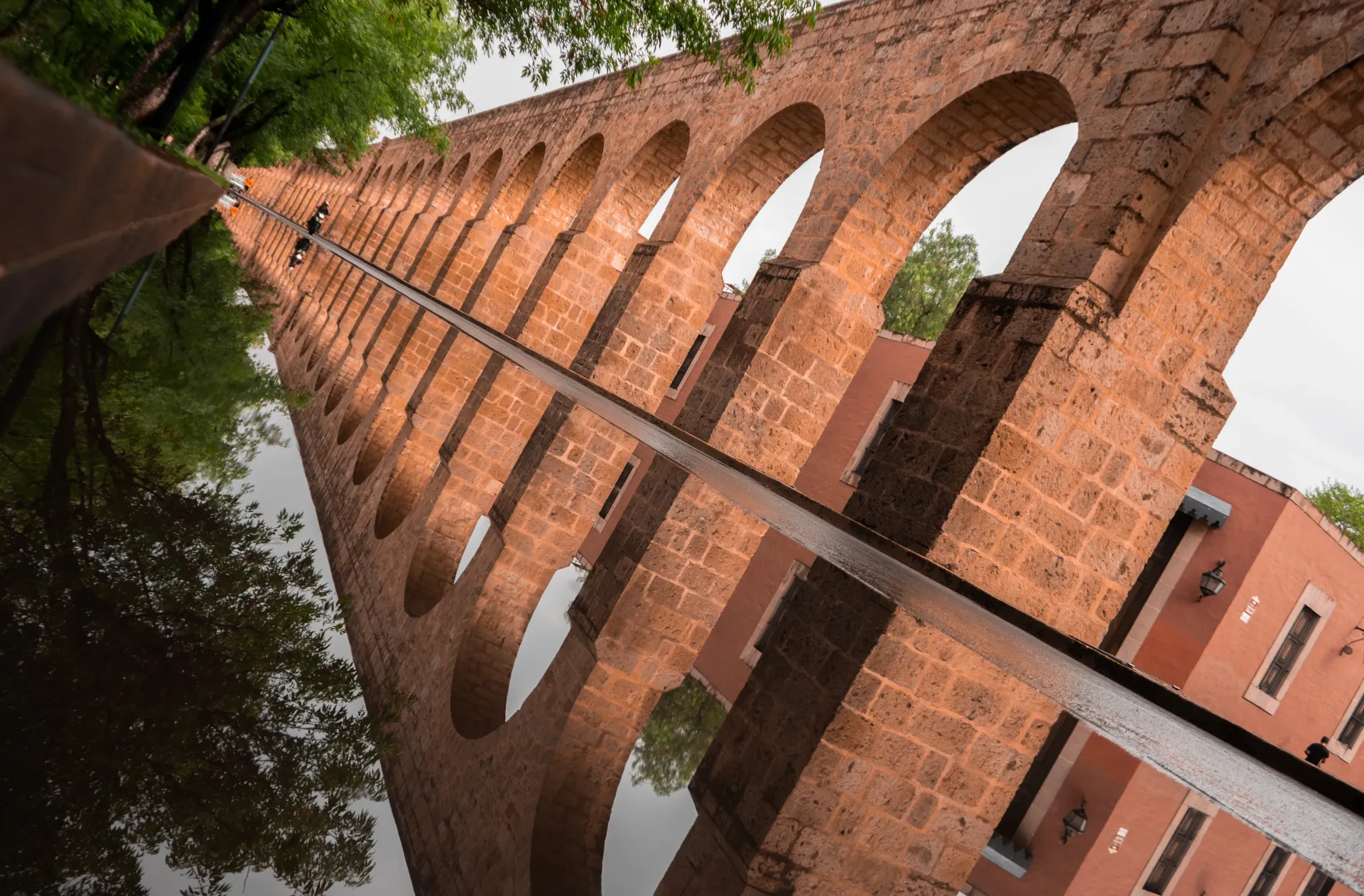 A brick bridge is reflected in a puddle of water.