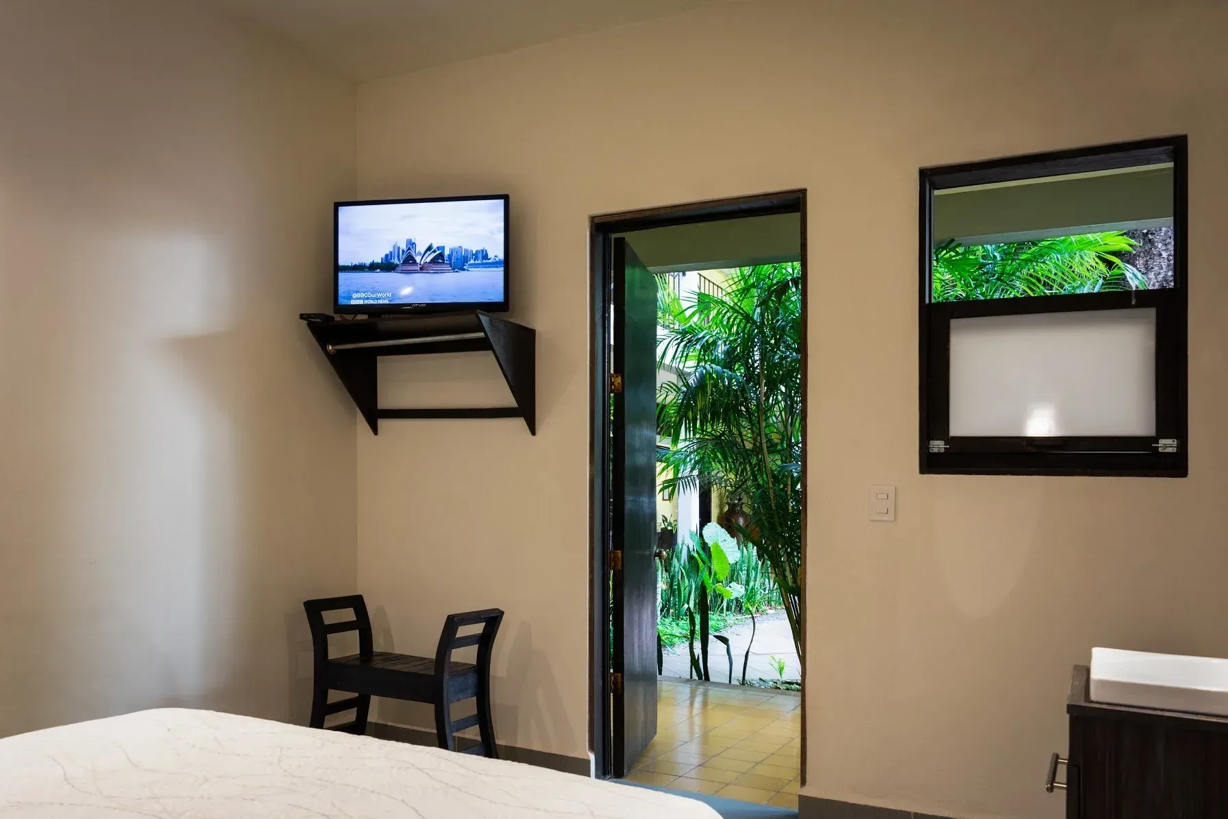 Un dormitorio con una cama y un televisor en la pared.