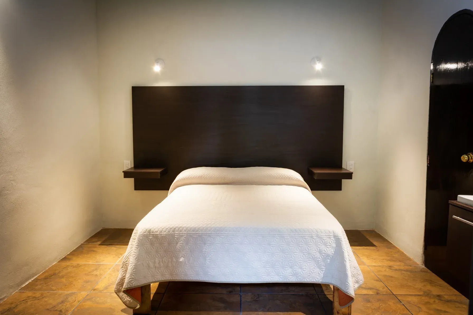 Un dormitorio con una cama, mesitas de noche y una puerta.