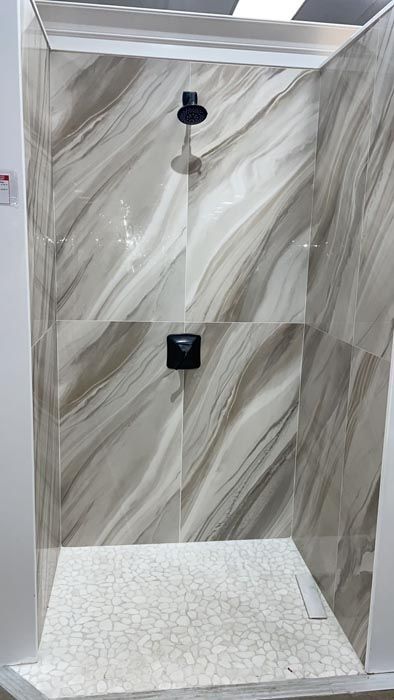 Tiled shower stall with handheld showerhead and built-in shelf