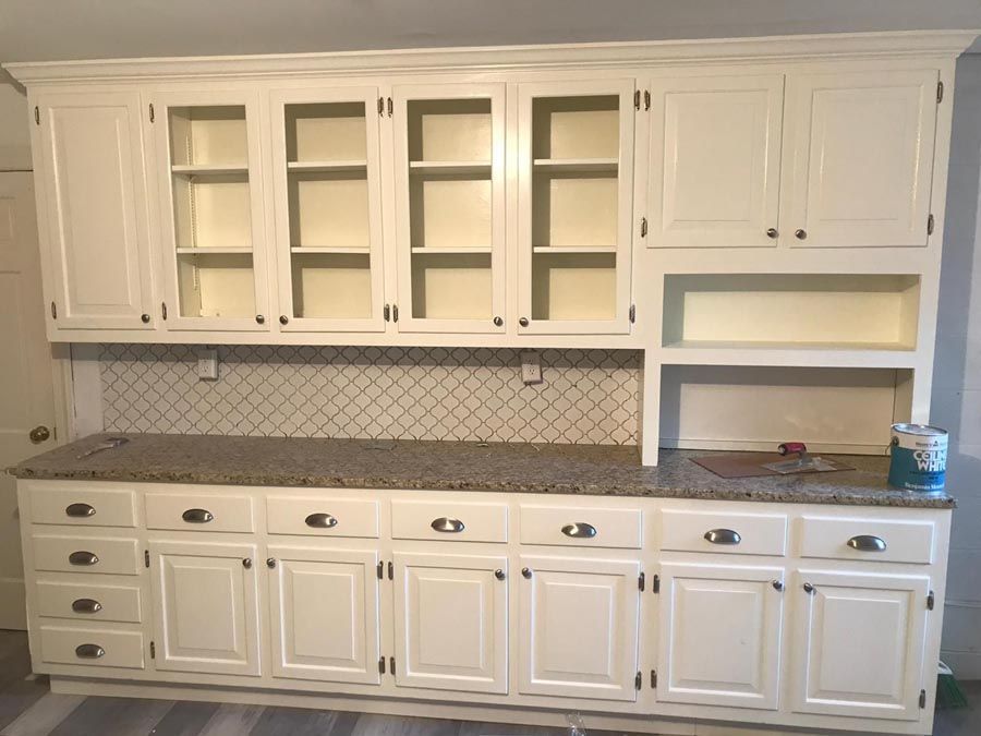 White kitchen wall with built-in cabinets, open shelves, granite countertop, and tiled backsplash