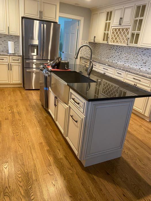 Modern kitchen with stainless steel appliances, black island countertop, white cabinets, and wood floors