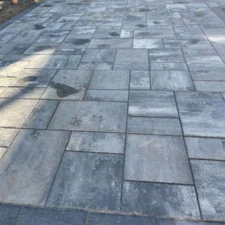 Stone-paved walkway with gray rectangular tiles and sunlight casting shadows.