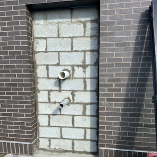 Brick wall niche with two exposed pipes between two dark brick walls