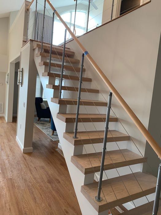 Modern staircase with wood steps, glass railings, and metal handrails in a bright home interior