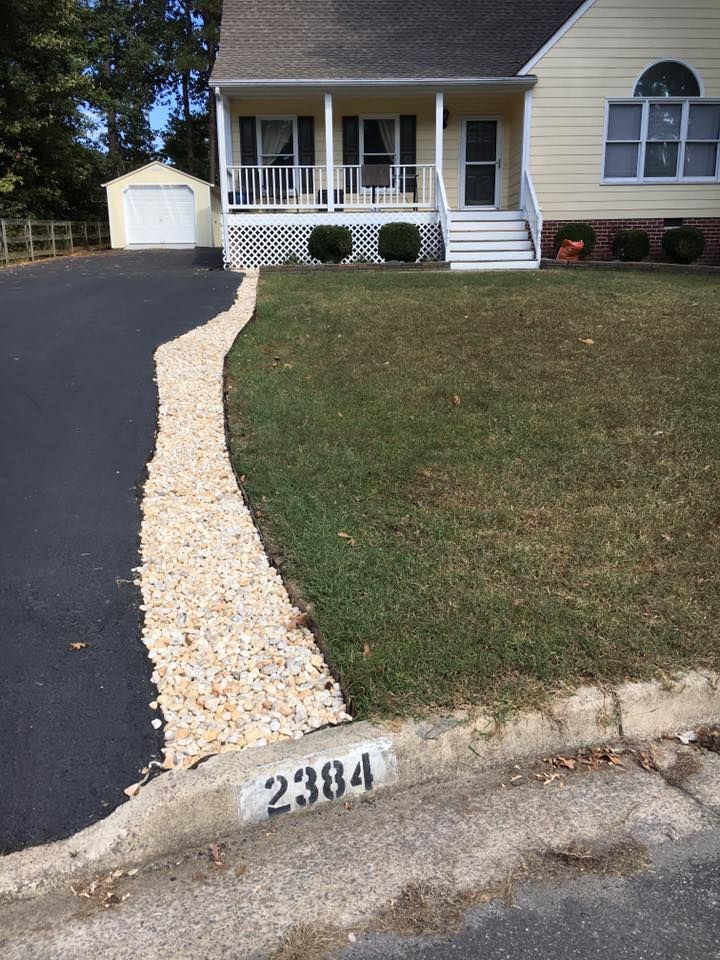 Suburban house with a white porch, driveway, and gravel walkway leading to the front steps.