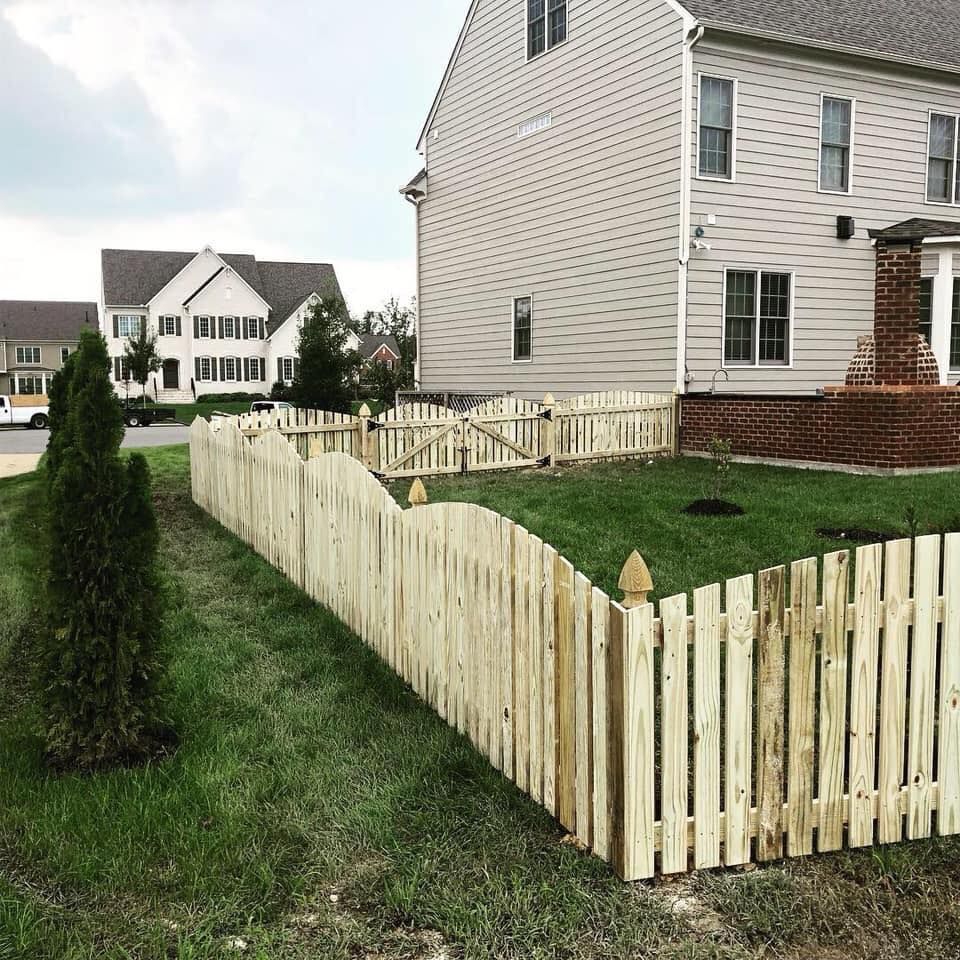 Suburban homes with a white picket fence enclosing a green yard under overcast skies