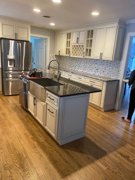 Bright modern kitchen with stainless steel appliances, white cabinets, black island countertop, and wood floors