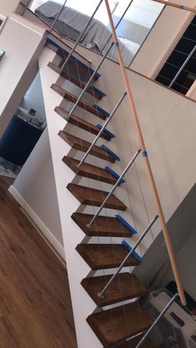 Floating wooden staircase with blue cable railings in a modern interior
