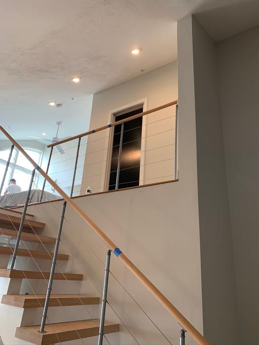 Staircase with wooden steps, glass railing, and recessed ceiling lights in a modern interior.