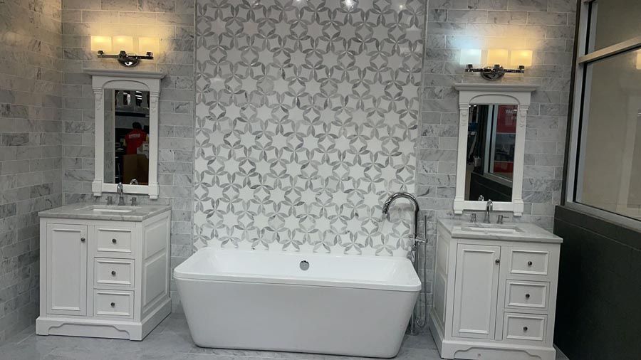 Bright bathroom with freestanding tub, twin vanities, and patterned accent wall, lit by wall sconces