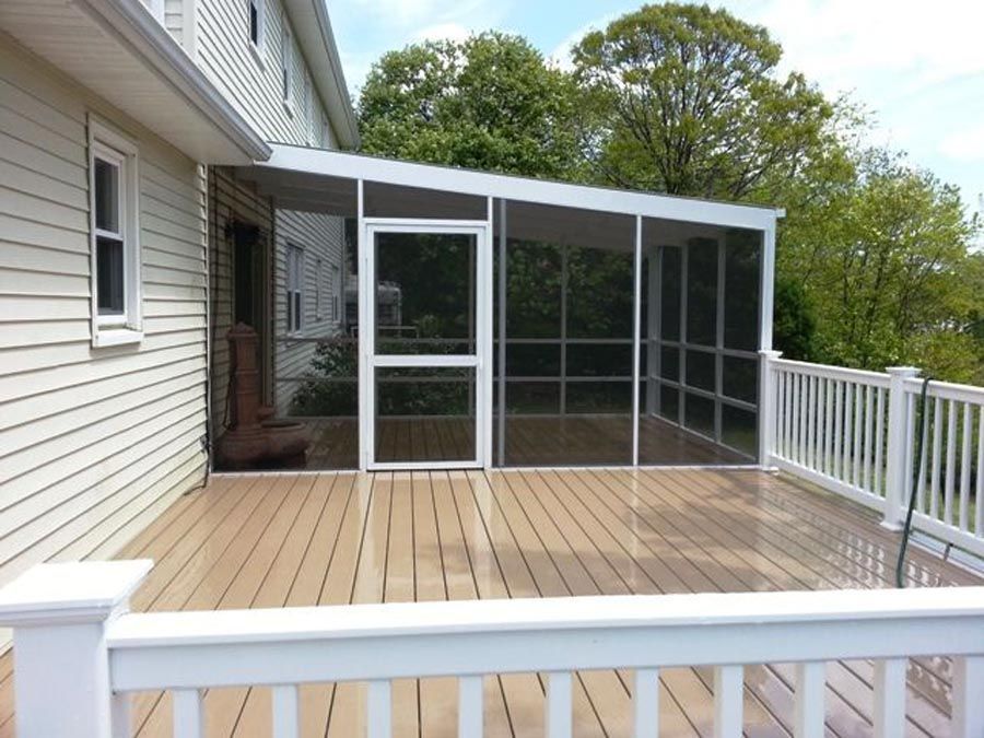 Backyard deck with white railing and screened sunroom attached to a house