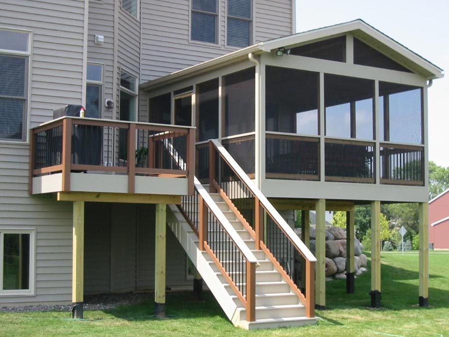 Raised backyard deck with stairs, screened porch, and wooden railings attached to a house