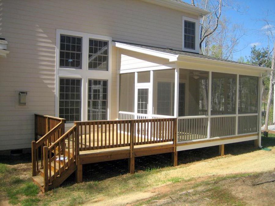 Wooden deck and screened porch attached to the back of a beige house on a sunny day