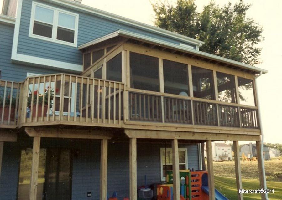 Raised wooden deck attached to a blue house with screened porch and stairs underneath