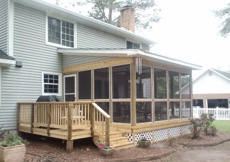 Rear house deck and screened porch with light wood railings, attached to a gray home.