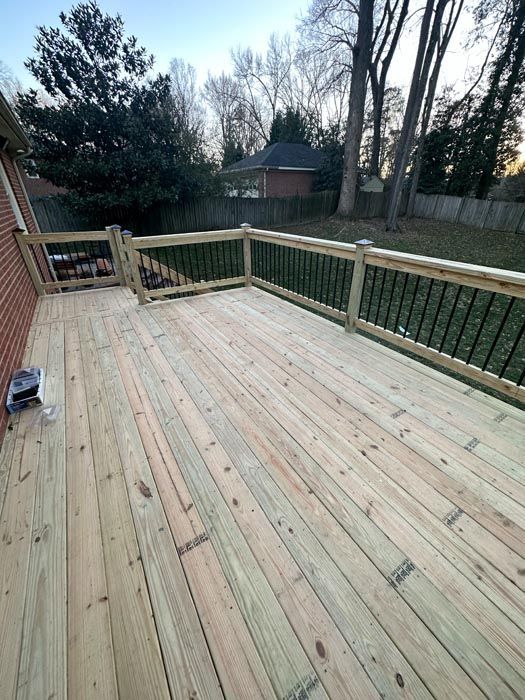 Wooden backyard deck with railings, overlooking a grassy yard and trees at dusk