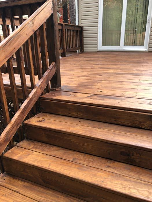 Wooden deck stairs with railing leading to a patio door on a weathered deck