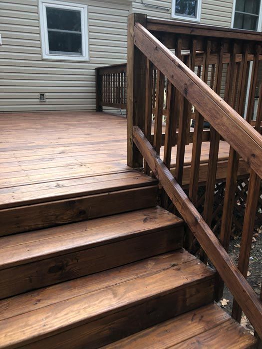 Wooden deck with steps and railing beside a house wall