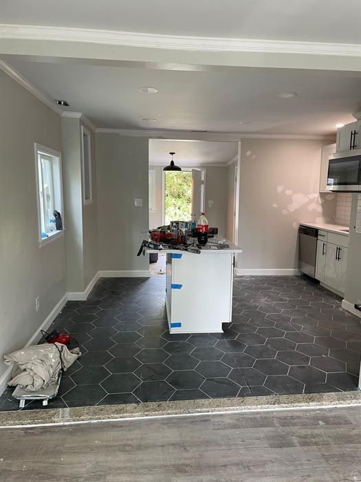 Unfurnished kitchen with gray tile floor, white cabinets, and a central island with flowers.