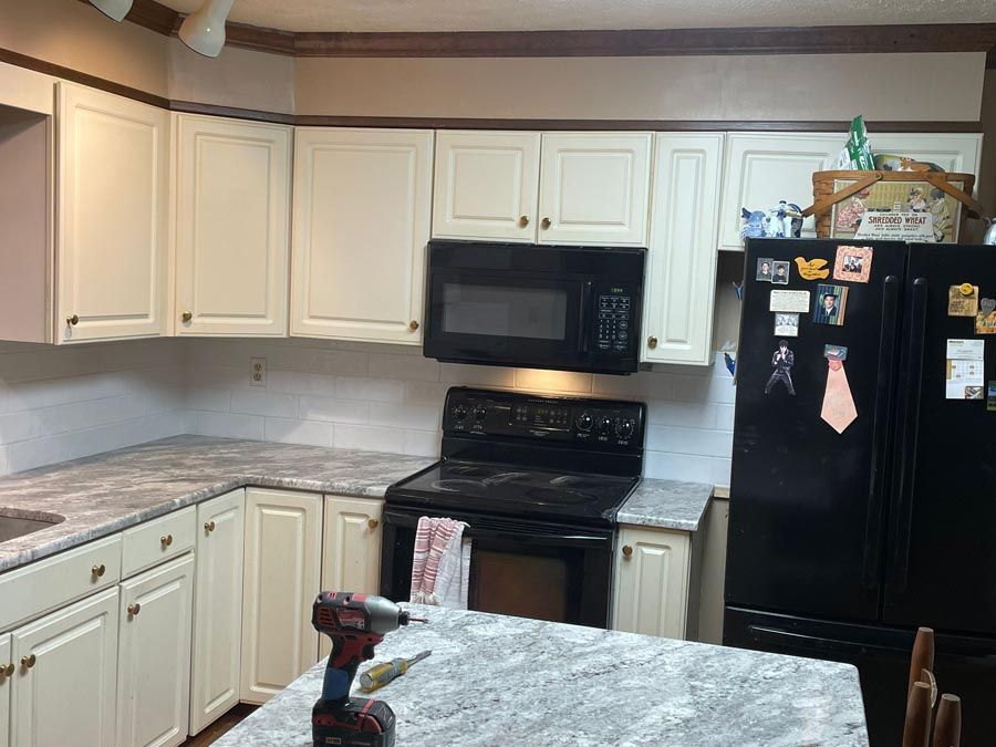 White kitchen with cabinets, black stove and fridge, and granite countertops.