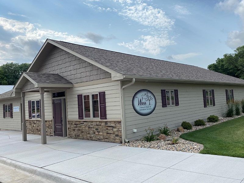 Tan and beige commercial building with green trim, sidewalk, and parking lot.