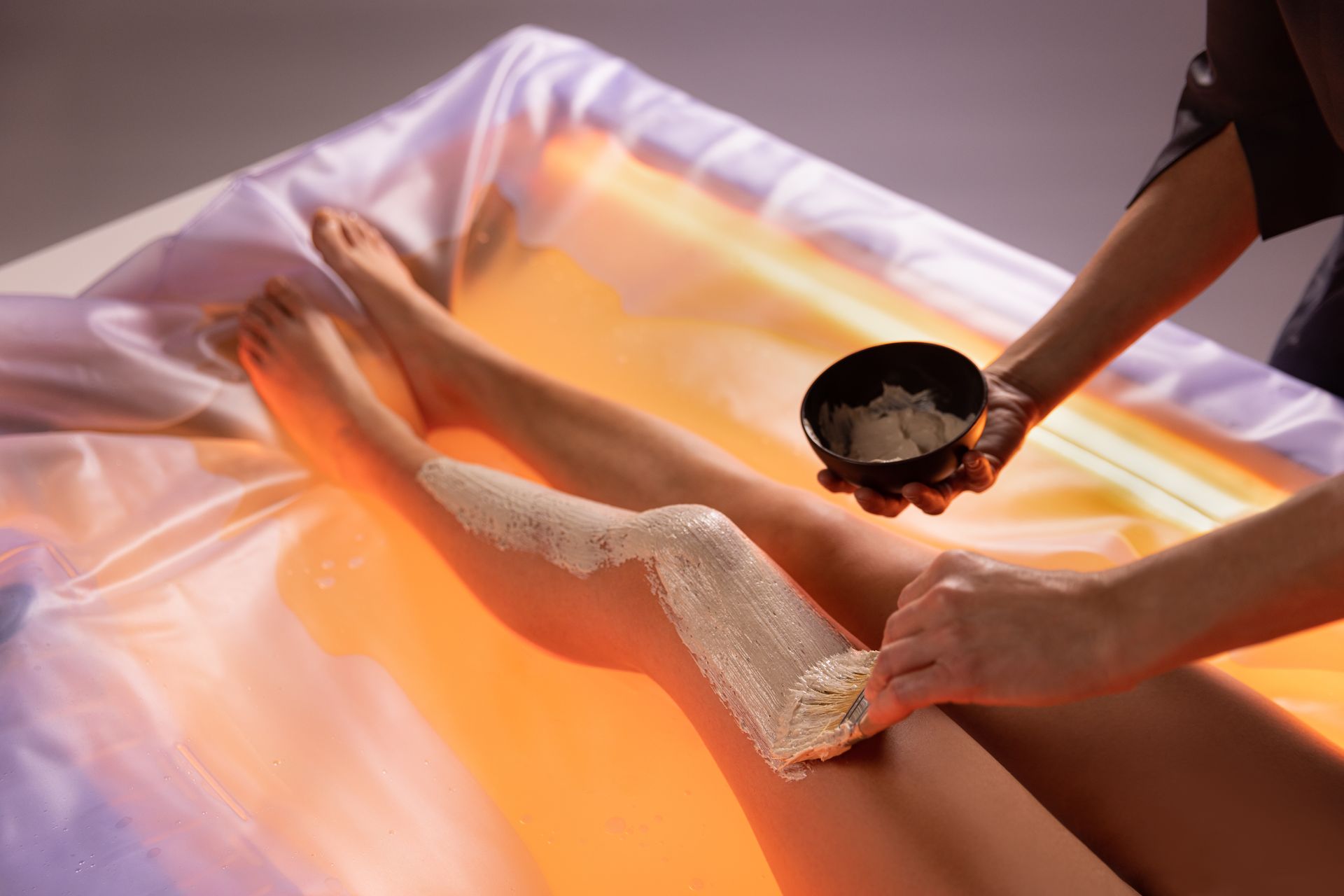 Una donna si fa massaggiare con una ciotola di crema sulla gamba.