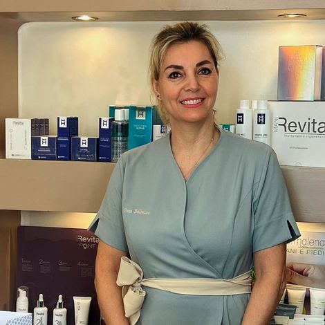 Donna seduta che si tocca i capelli sorridendo Donna felice dopo trattamento da Oasi Bellezza