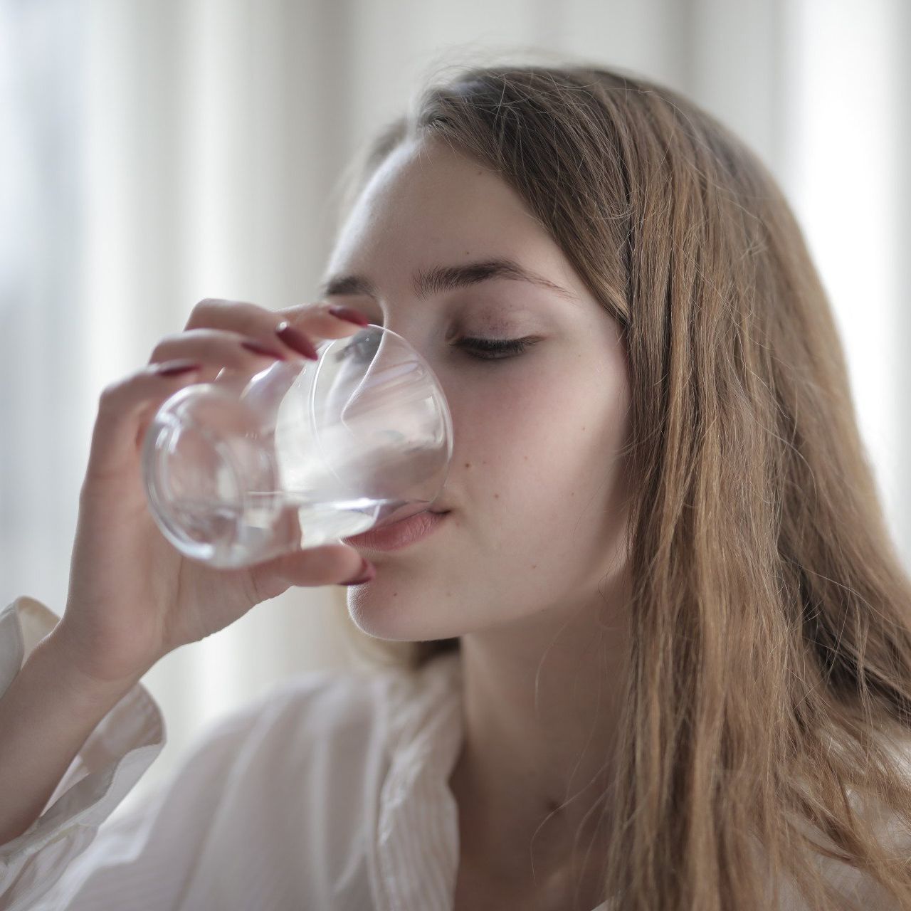 Una donna beve acqua da un bicchiere.