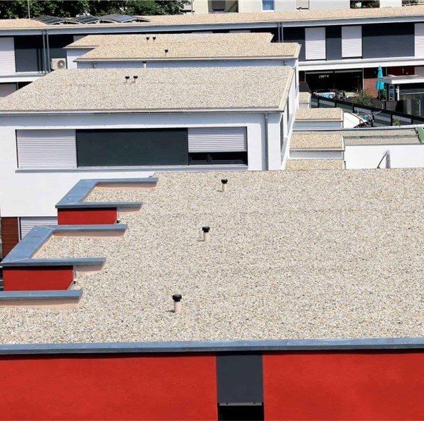 Roofs of several white and red buildings with gravel surfaces.