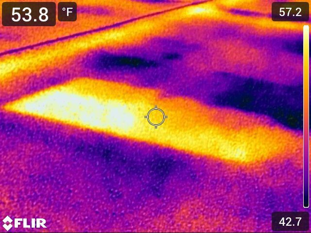 Infrared view of a surface showing temperature differences; warmer areas are yellow/orange, cooler areas are purple.